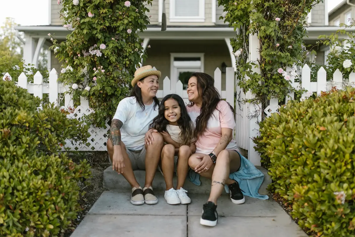 Family of three sitting together on the front steps of their home